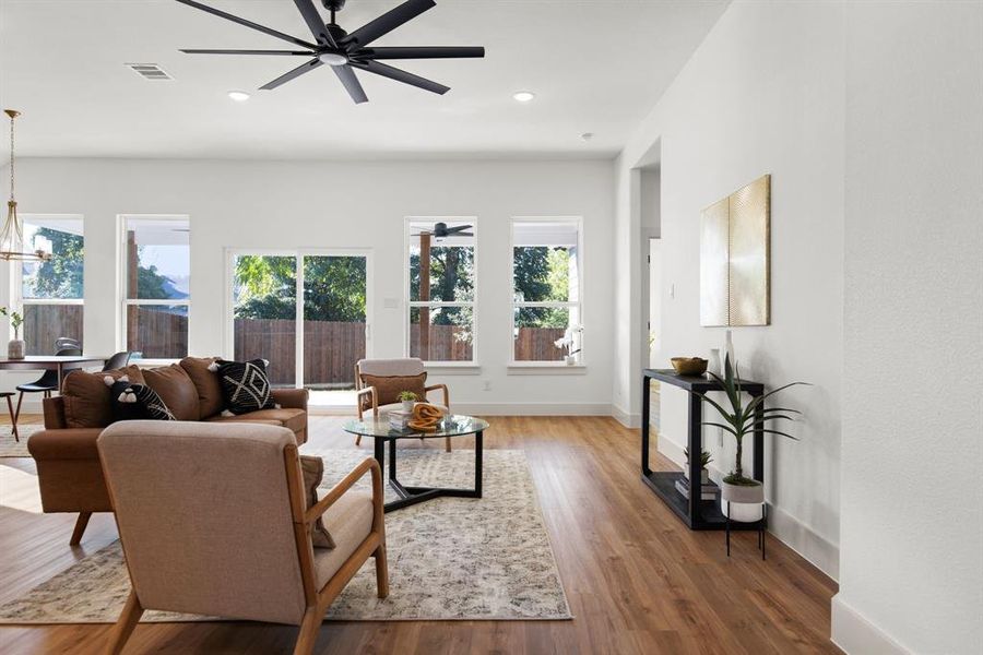 Living room with ceiling fan with notable chandelier and hardwood / wood-style flooring