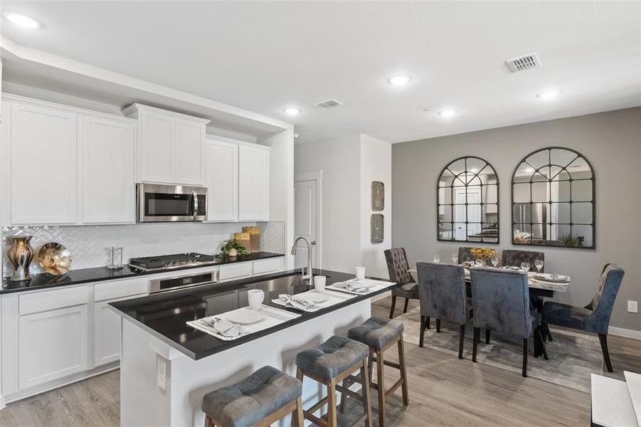 Kitchen featuring light wood-type flooring, appliances with stainless steel finishes, sink, an island with sink, and a kitchen breakfast bar