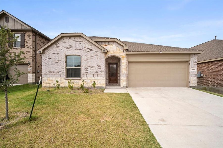 View of front of property featuring a front yard and a garage