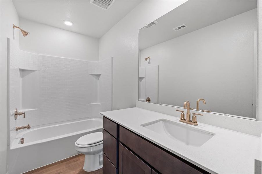 Full bathroom featuring wood-style floors, vanity, toilet, and  shower combination