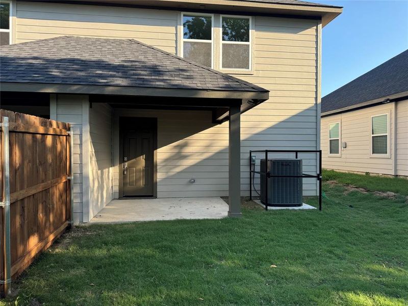 Back of property featuring central AC unit, a lawn, and a patio