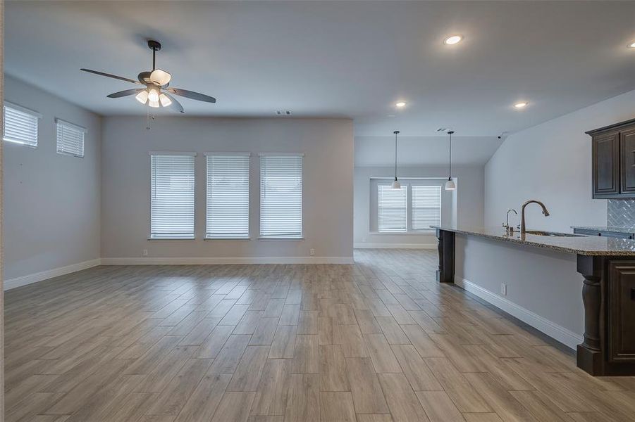 Unfurnished living room featuring sink, light wood-type flooring, and ceiling fan