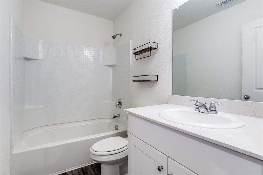 Full bathroom featuring tub / shower combination, wood-type flooring, toilet, and vanity with extensive cabinet space