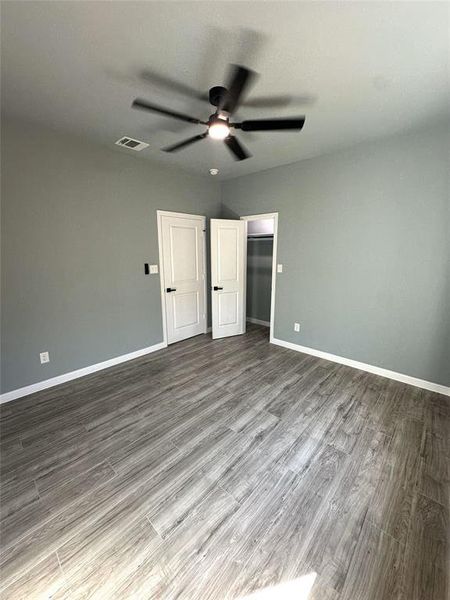 Unfurnished bedroom featuring a spacious closet, a closet, light wood-type flooring, and ceiling fan