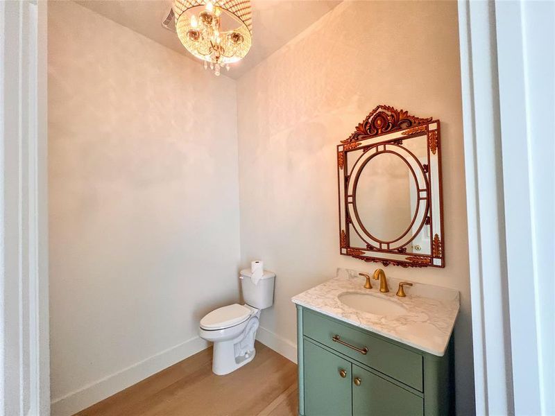Guest Bathroom with wood-type flooring, an inviting chandelier, toilet, and large vanity