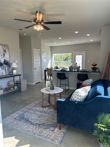 Living room featuring ceiling fan and concrete flooring