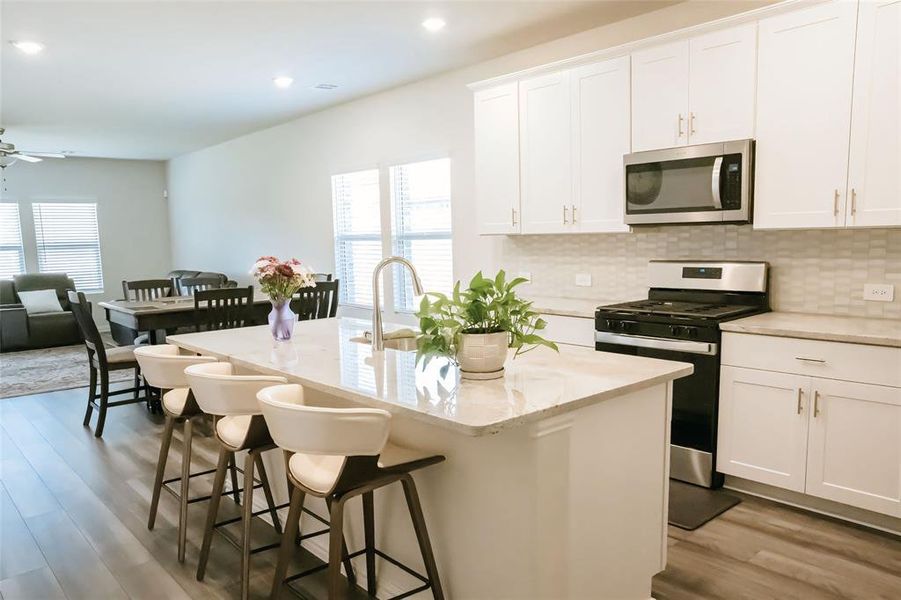 Kitchen featuring ceiling fan, a center island with sink, stainless steel appliances, and white cabinetry