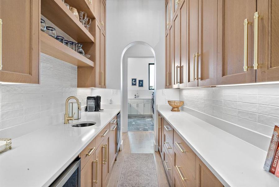 Kitchen featuring sink, light wood-type flooring, wine cooler, and backsplash