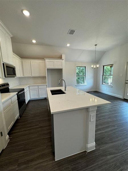 Kitchen featuring dark hardwood / wood-style flooring, range, pendant lighting, sink, and lofted ceiling