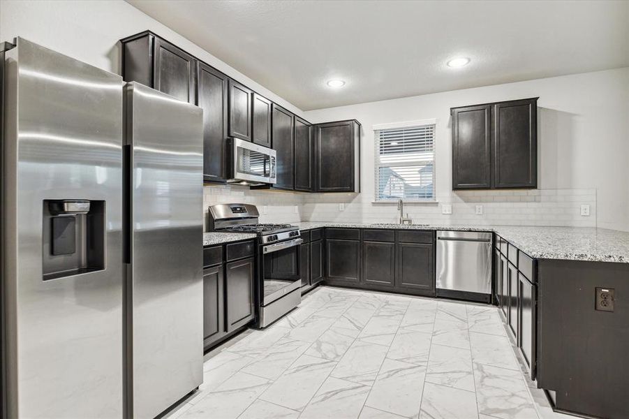 Kitchen with stainless steel appliances. Refrigerator stays