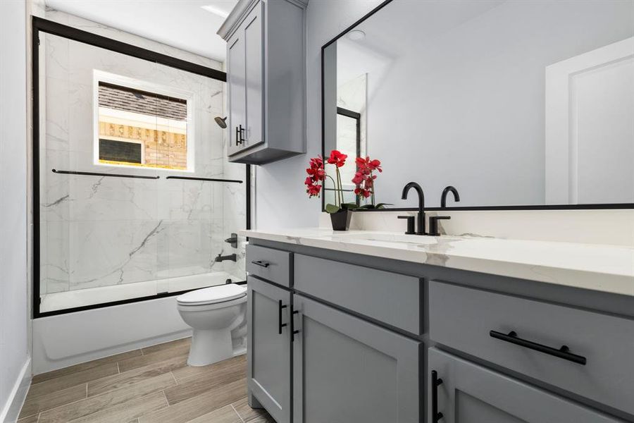 Full bathroom with combined bath / shower with glass door, vanity, and toilet