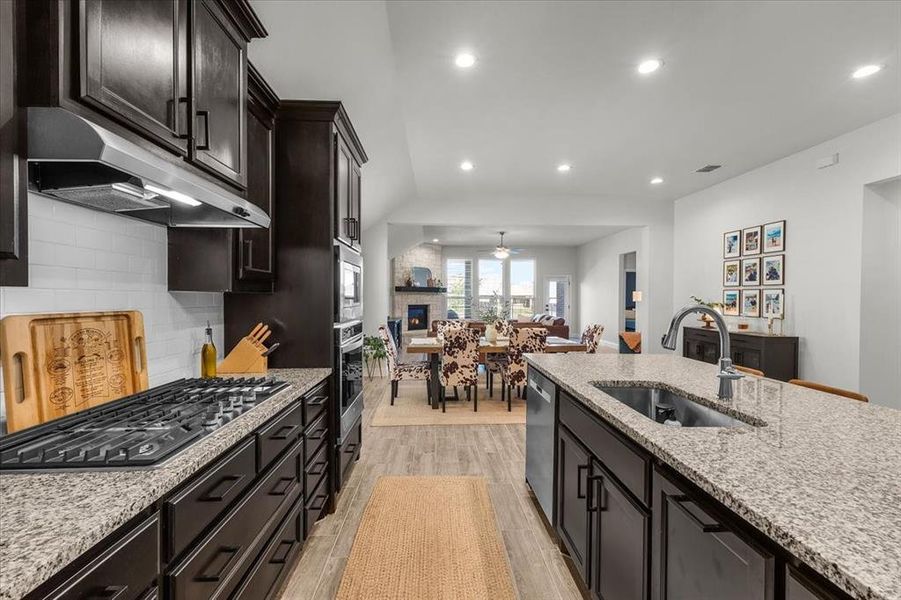 Kitchen with tasteful backsplash, stainless steel appliances, sink, a fireplace, and light hardwood / wood-style floors