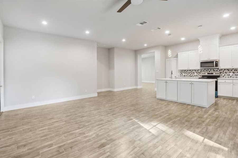 Kitchen with stainless steel appliances, light hardwood / wood-style floors, ceiling fan, and white cabinets