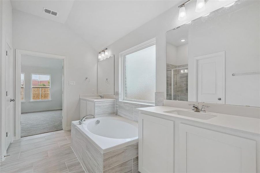 Bathroom with vanity, lofted ceiling, and separate shower and tub