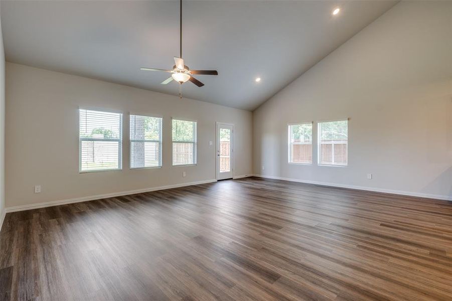 Unfurnished living room featuring high vaulted ceiling, ceiling fan, and dark hardwood / wood-style floors
