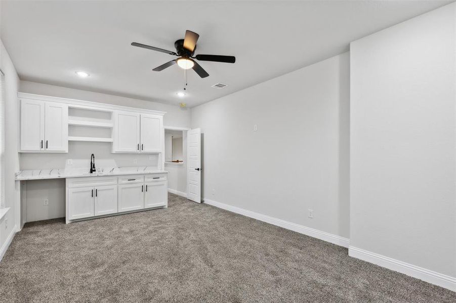 Kitchen featuring white cabinetry, ceiling fan, and carpet