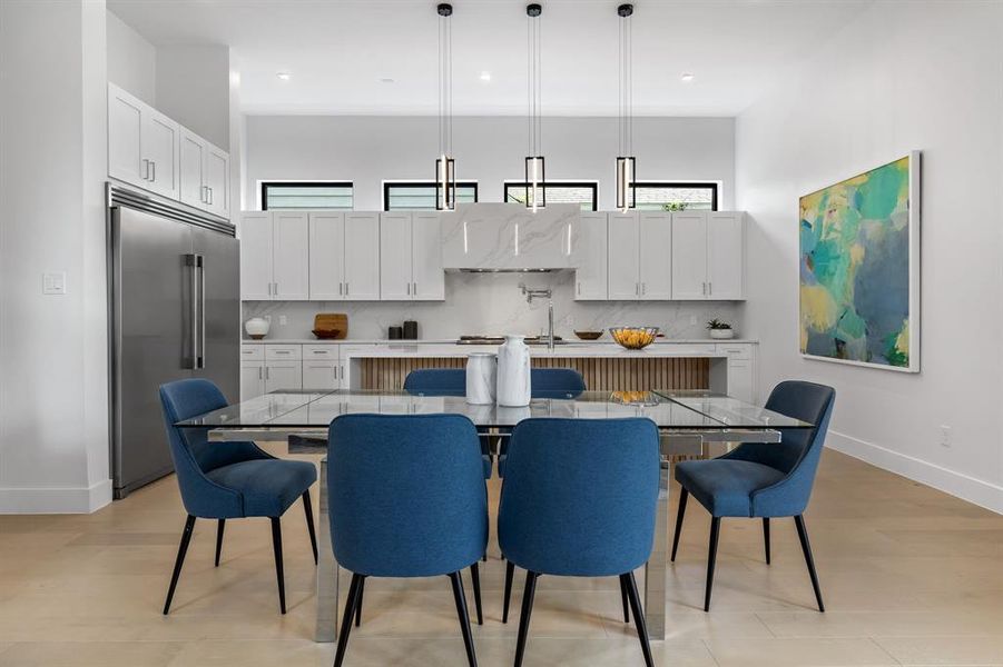 Kitchen featuring a kitchen island with sink, plenty of natural light, decorative light fixtures, and stainless steel built in fridge