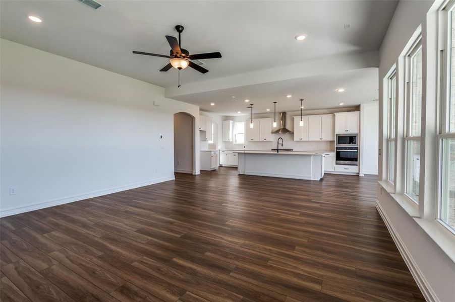 Unfurnished living room with sink, ceiling fan, and dark hardwood / wood-style flooring