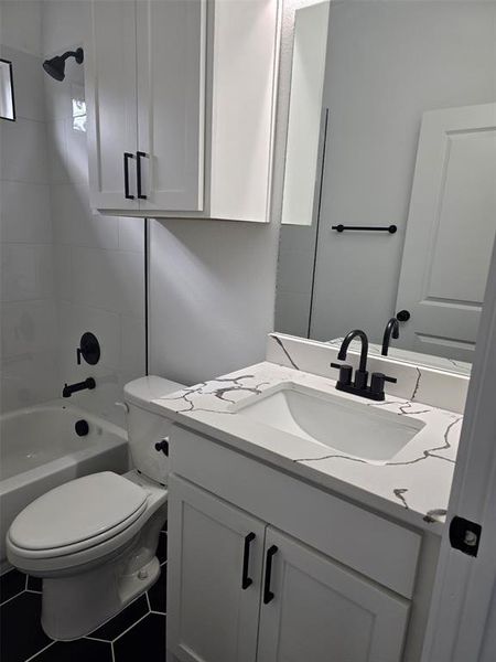 Full bathroom with tiled shower / bath combo, vanity, toilet, and tile patterned floors