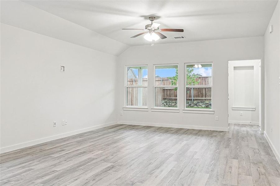 Empty room with light hardwood / wood-style floors, lofted ceiling, and ceiling fan