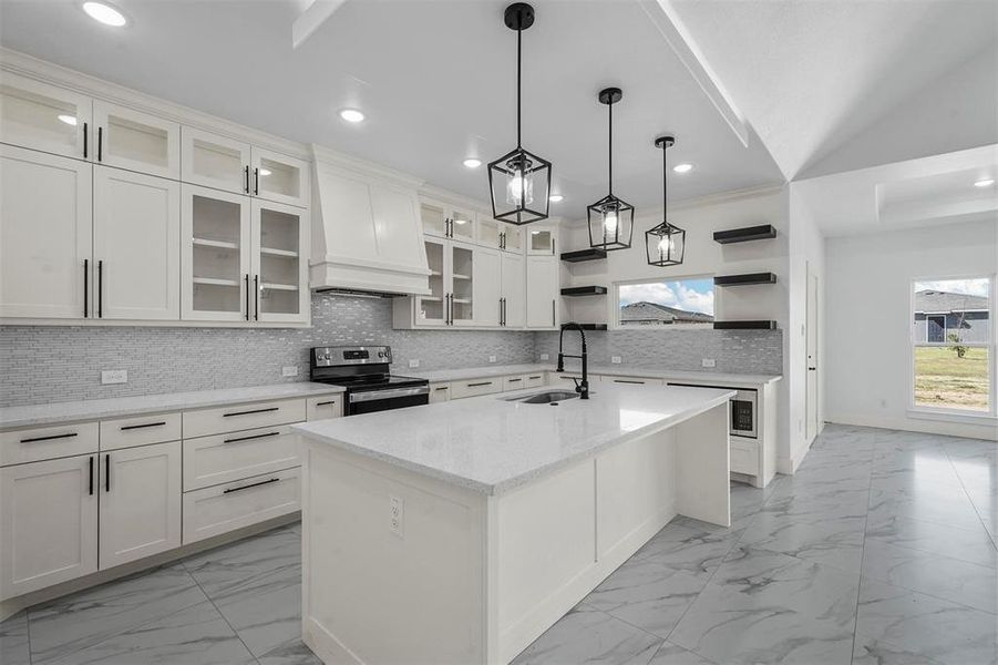 Kitchen featuring a kitchen island with sink, sink, stainless steel electric range, and white cabinetry