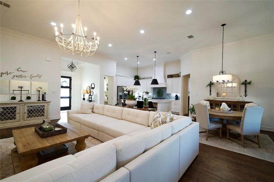 Living room featuring ornamental molding, an inviting chandelier, and dark wood-type flooring