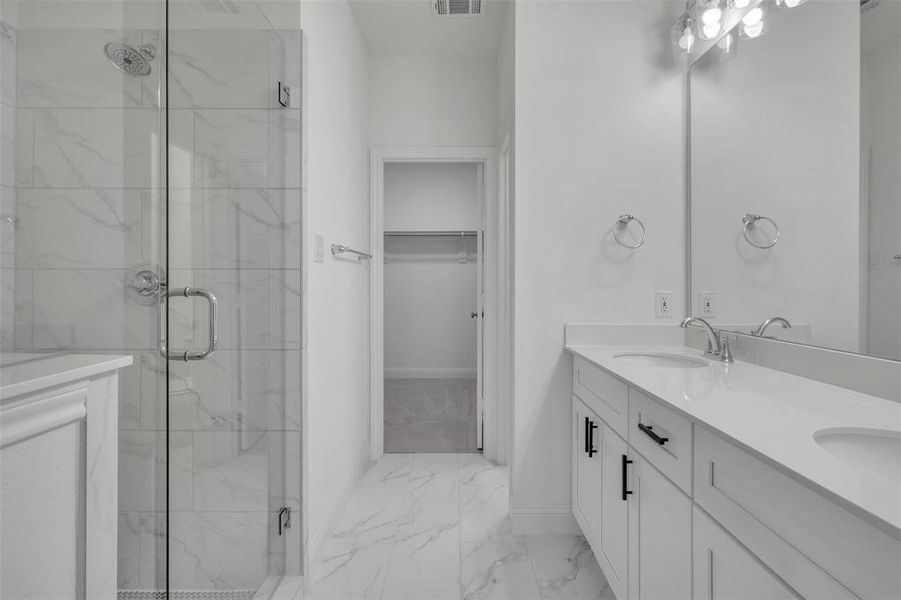 Primary bathroom with tile floors, an enclosed shower, and dual bowl vanity