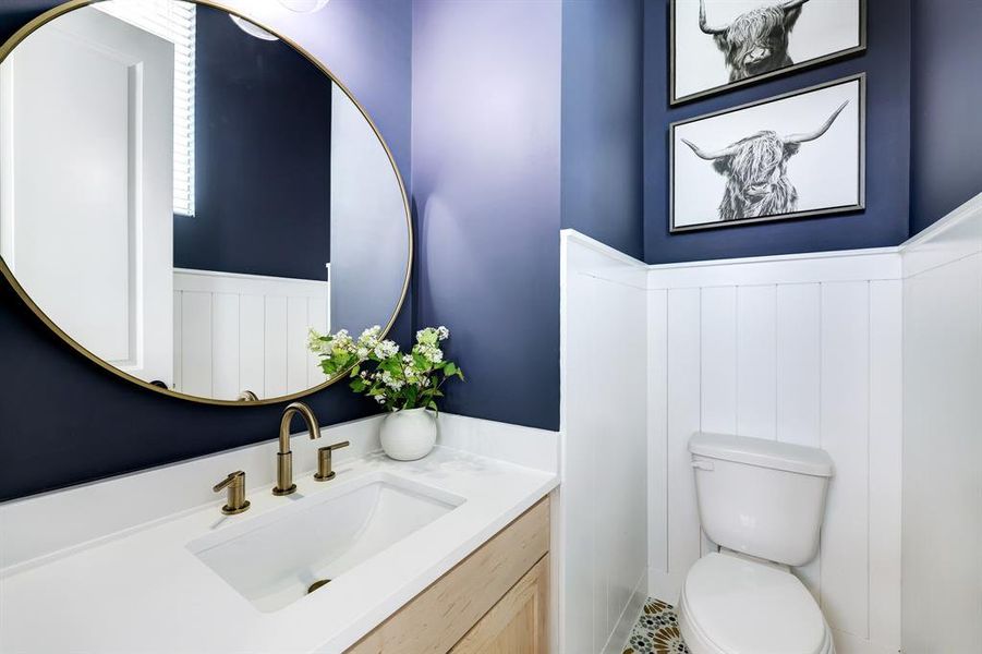 Chic Powder Room: Featuring elegant navy walls, a sleek white vanity, and striking gold accents, this stylish half bath adds a touch of sophistication to your home.