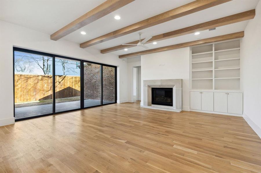 Unfurnished living room featuring light wood-type flooring, beamed ceiling, and ceiling fan