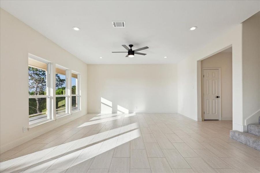 Unfurnished room with ceiling fan and light tile floors