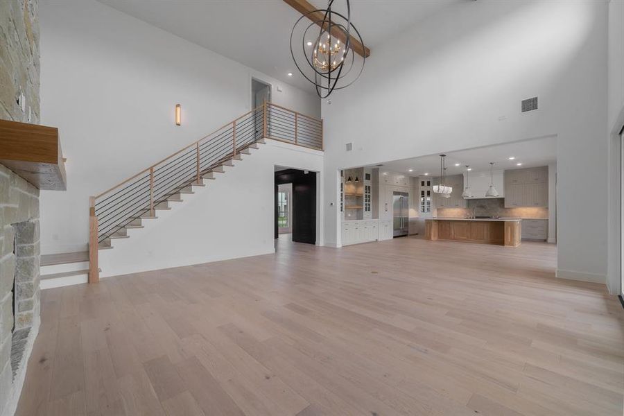 Unfurnished living room with light hardwood / wood-style floors, a high ceiling, and an inviting chandelier