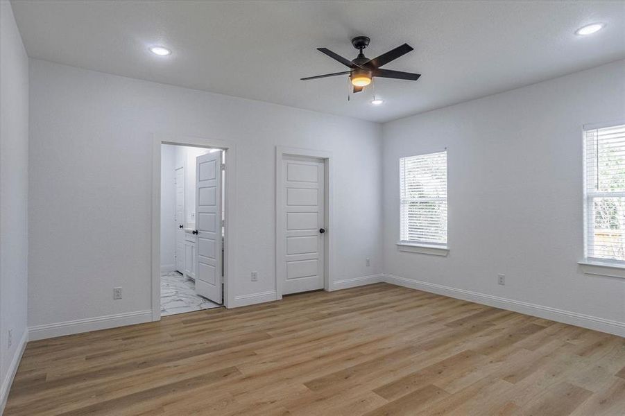 Unfurnished bedroom featuring light hardwood / wood-style floors, a closet, connected bathroom, and ceiling fan