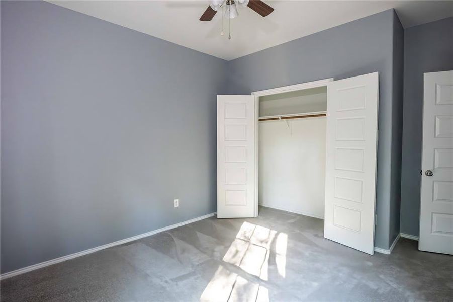 Unfurnished bedroom featuring a closet, dark carpet, and ceiling fan