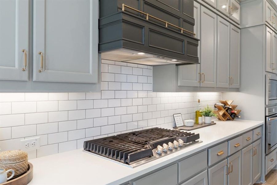 Kitchen with backsplash, appliances with stainless steel finishes, and premium range hood