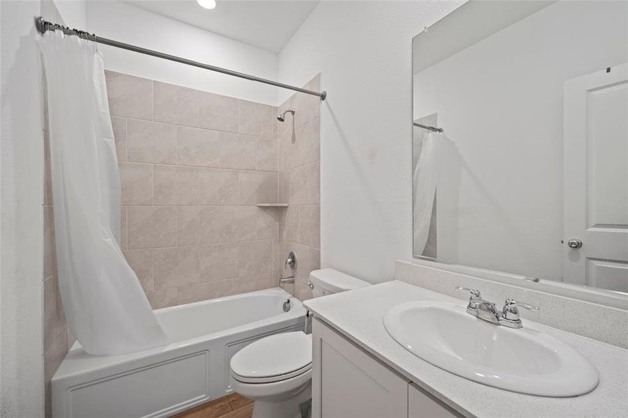 Full bathroom with vanity, shower / bath combination with curtain, and toilet