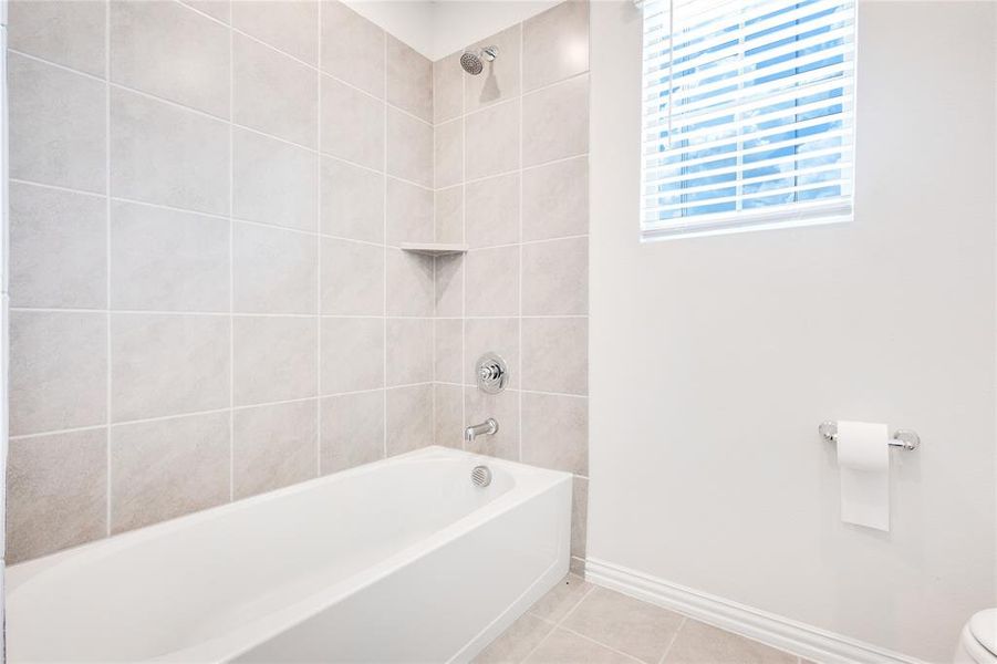Bathroom with tile patterned flooring, tiled shower / bath combo, and toilet