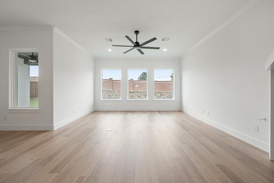 Unfurnished room with light hardwood / wood-style flooring, ornamental molding, and ceiling fan