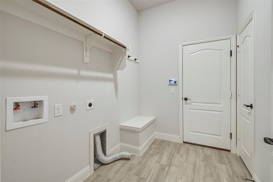 Laundry area with hookup for a gas dryer, hookup for an electric dryer, hookup for a washing machine, and light wood-type flooring