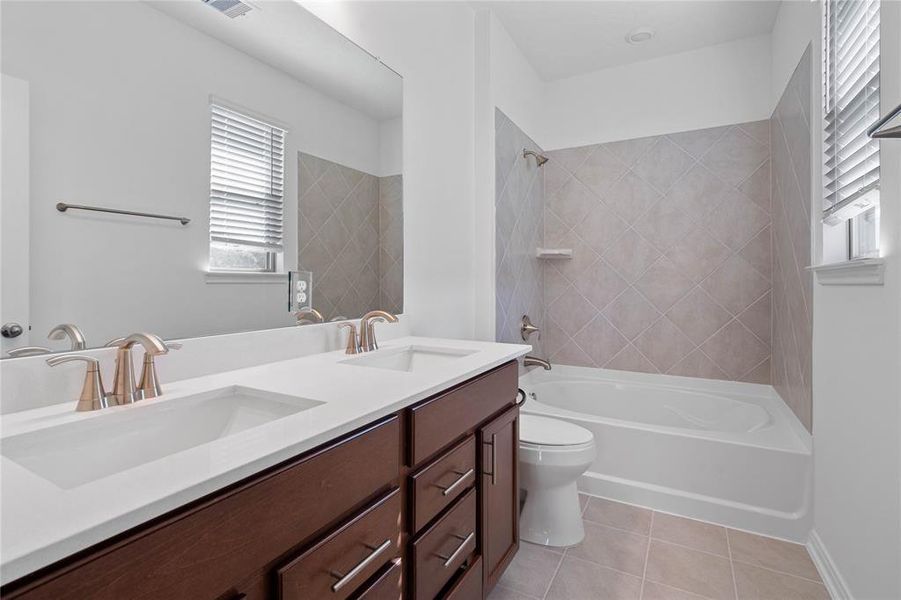 This primary bathroom is definitely move-in ready! Featuring an oversized tub/shower combo with tile surround, stained cabinets with light countertops, spacious walk-in closet with shelving, high ceilings, neutral paint, sleek and modern finishes.