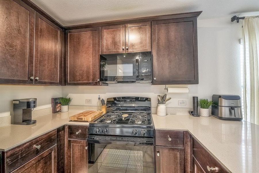 Kitchen featuring black appliances, dark brown cabinetry, and a textured ceiling