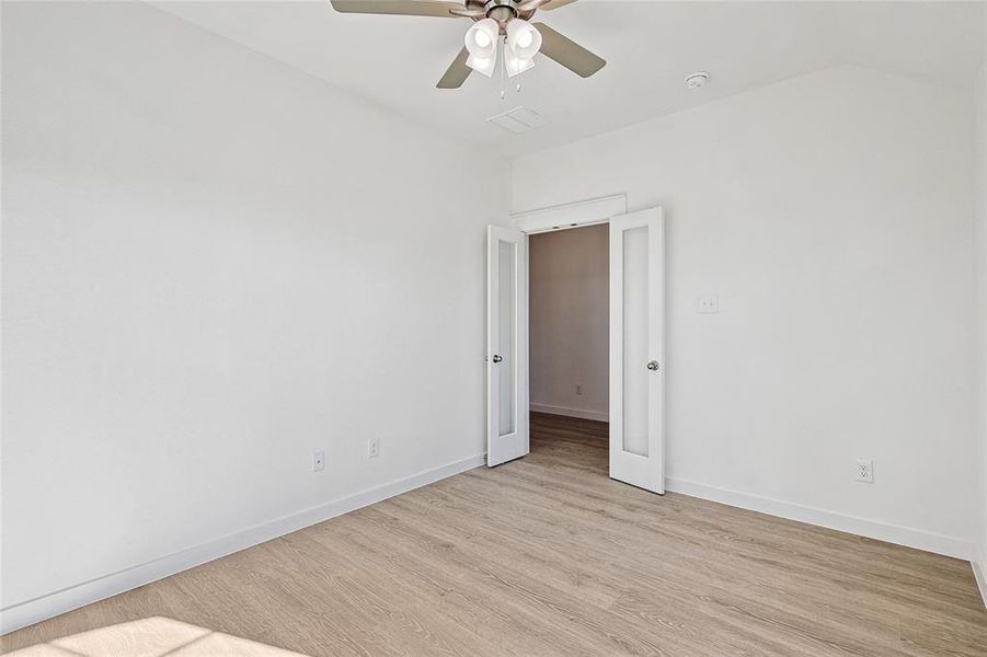 Spare room featuring ceiling fan, vaulted ceiling, and light hardwood / wood-style flooring