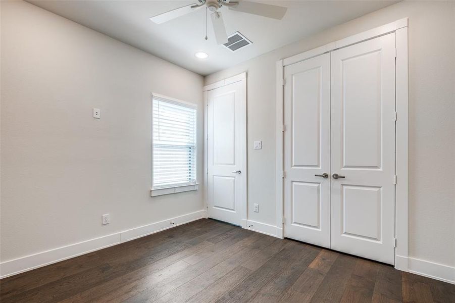 Secondary bedroom featuring ceiling fan and wood floors.