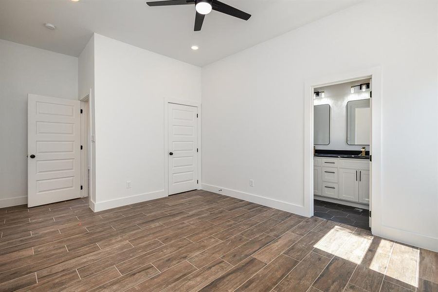 Unfurnished bedroom featuring a closet, sink, ensuite bathroom, dark hardwood / wood-style flooring, and ceiling fan