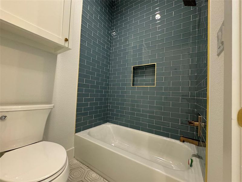 Bathroom with tile patterned floors, toilet, and tiled shower / bath