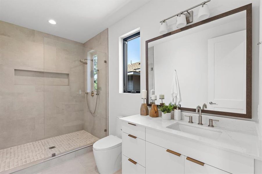 Bathroom featuring walk in shower, vanity, and toilet