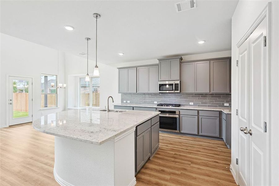 Kitchen with an island with sink, sink, light hardwood / wood-style flooring, and appliances with stainless steel finishes