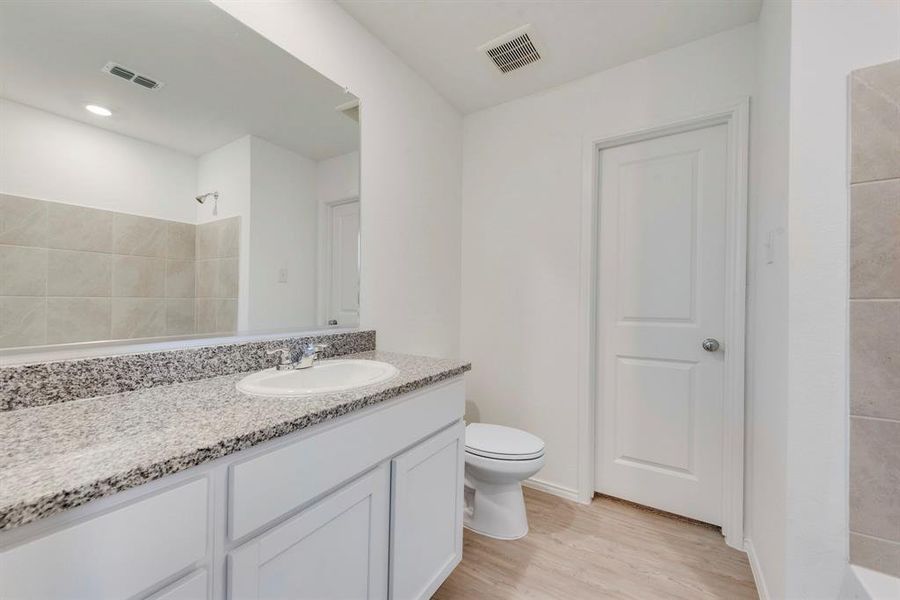 Full bathroom with vanity, shower / bath combination, wood-type flooring, and toilet
