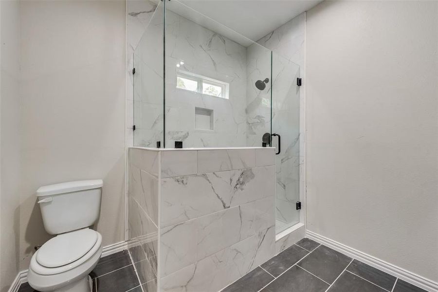 Bathroom with walk in shower, tile patterned floors, and toilet