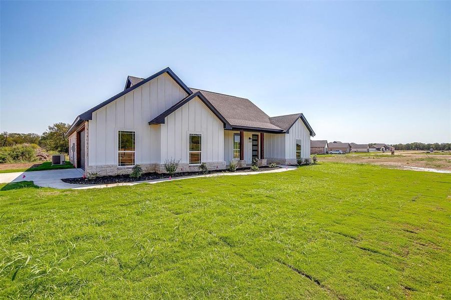 Modern farmhouse with a front yard and central air condition unit