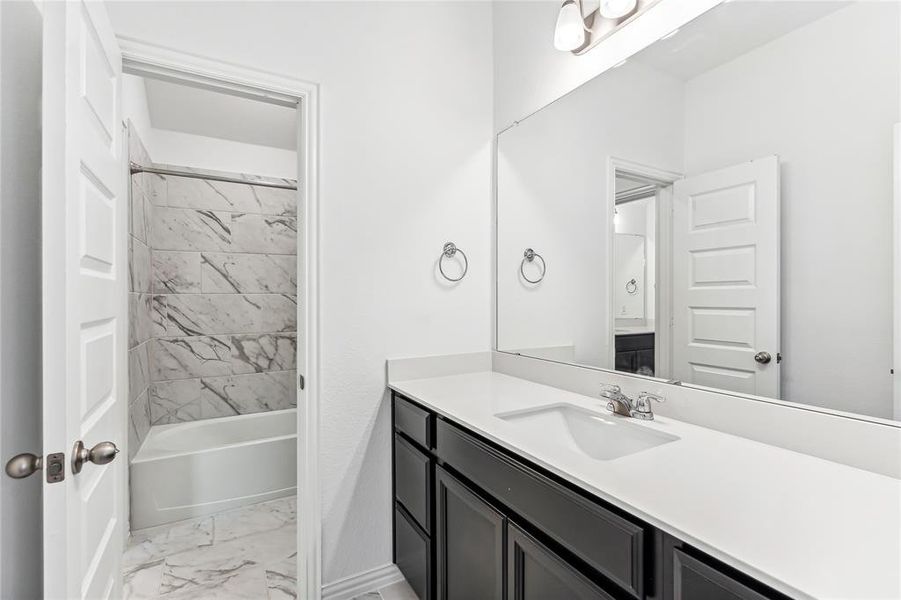 Bathroom with tiled shower / bath combo and vanity